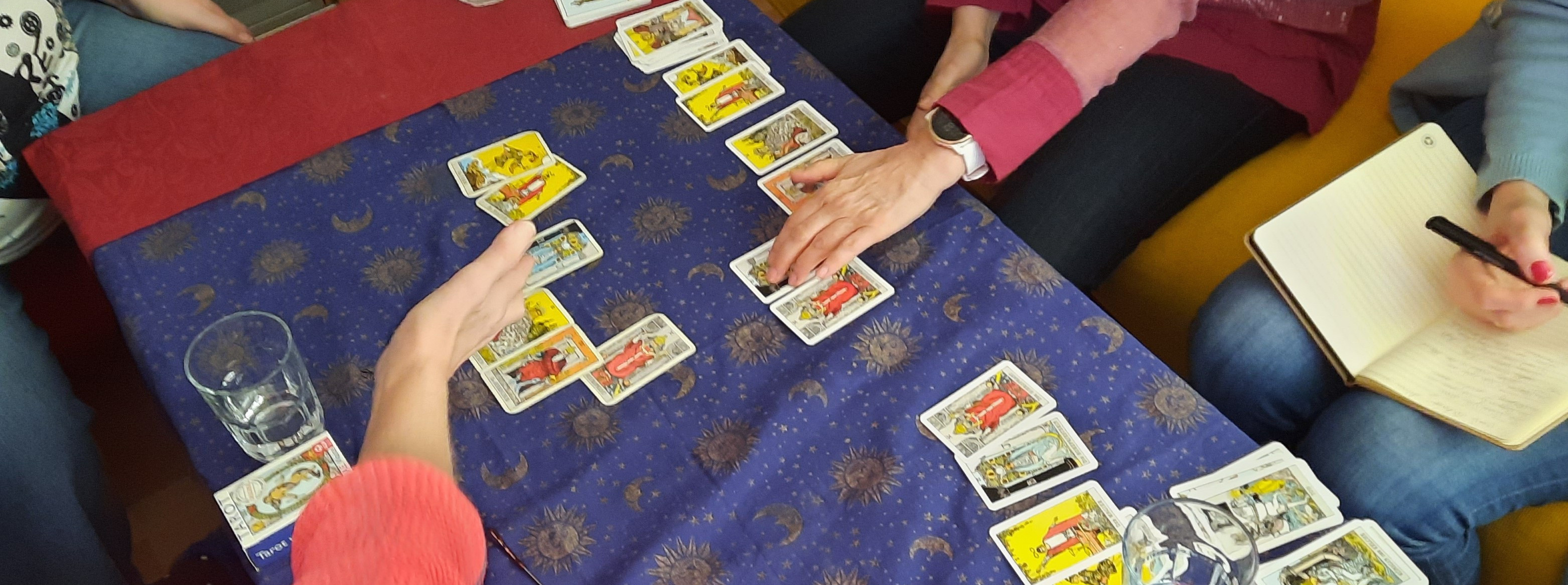 Ein Seminar für Tarot Kartenlegen. Hände zeigen zu den Karten und auf der Seite werden Notizen gemacht.